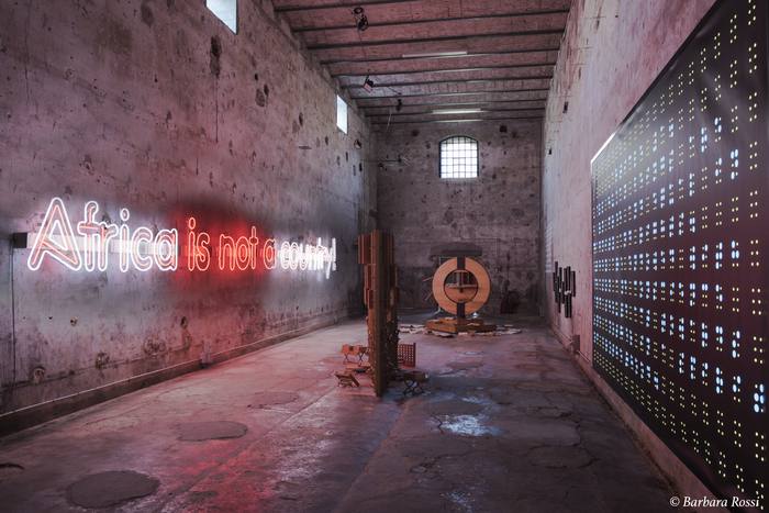 Elongated room with &laquo;Africa is not a country!&raquo; neon sign, archive structure and a dot-matrix light panel