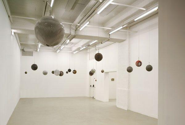 Sala bianca con numerose sfere di diverse dimensioni sospese al soffitto