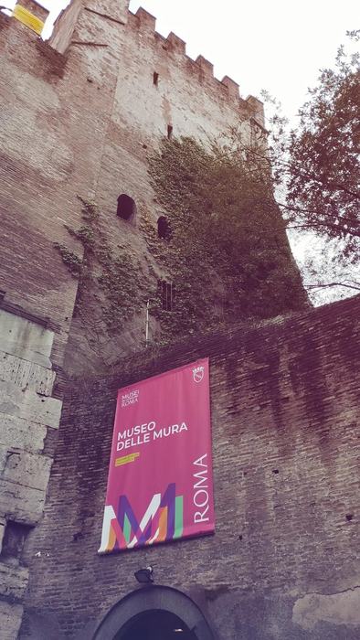 A tall brick tower with the Museo delle Mura banner hanging on the wall