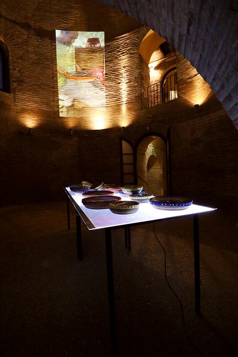 Frame drums on an illuminated table in a brick tower, with a projection on the wall