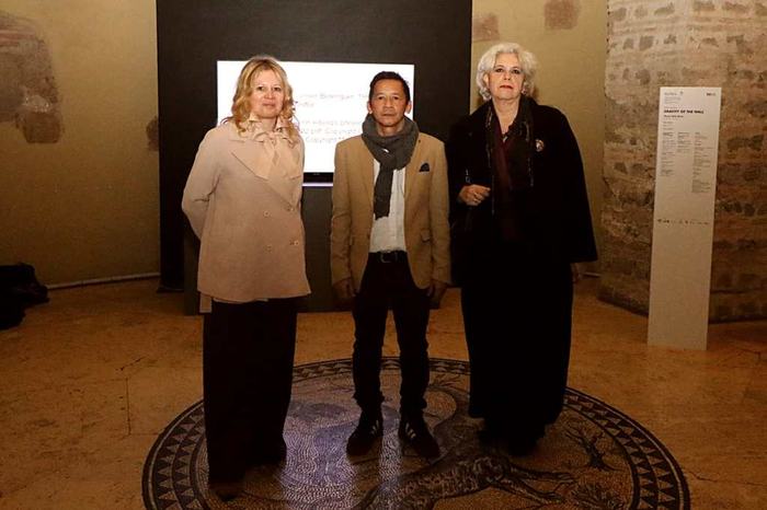 Three people posing in front of a screen inside the museum