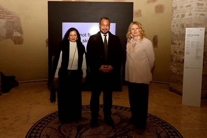 Three people posing in front of a screen inside the museum