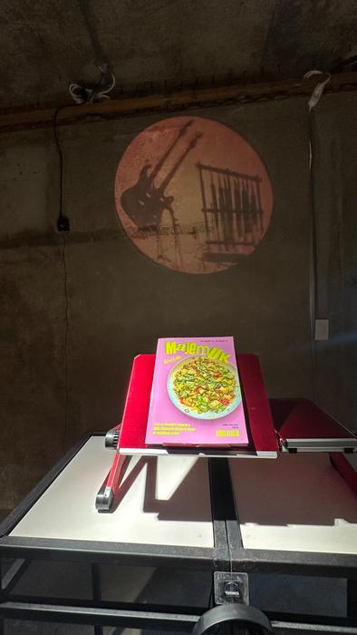 A printed book on a red stand on a table, with a circle of light projected on the wall behind