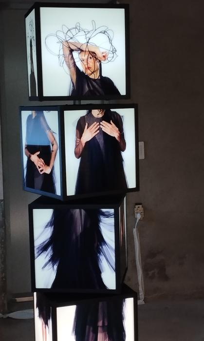 A tower of stacked light boxes, each showing a photographic portrait