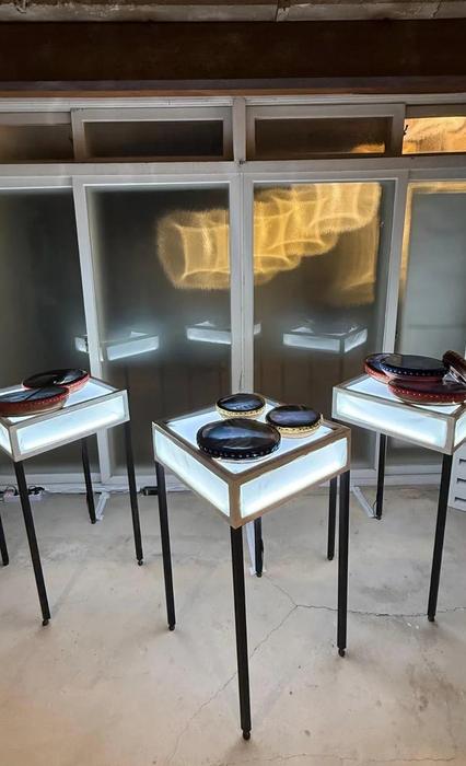 Round drum-like objects displayed on illuminated plinths in front of frosted windows