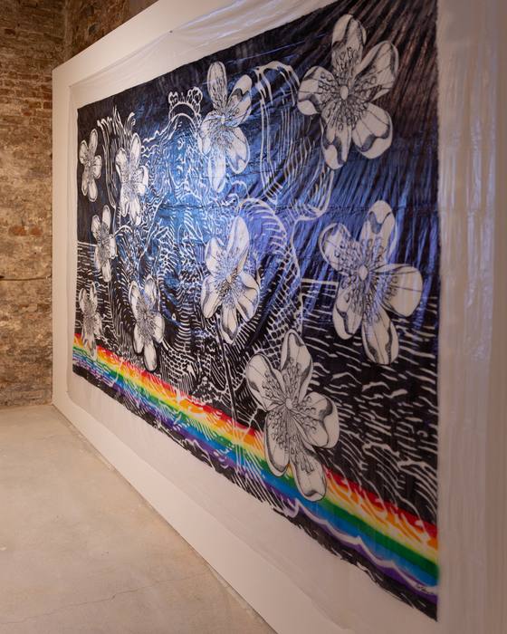 Large fabric work with black-and-white floral drawings and a rainbow-coloured stripe