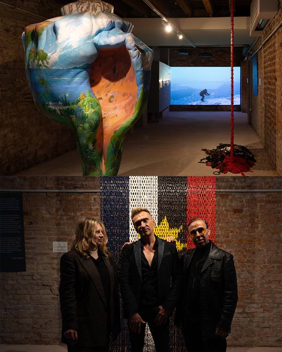 The three curators standing together in front of the chain curtain installation