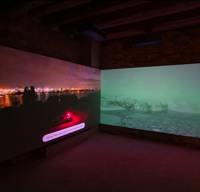 Two large video projections meeting at a corner in a dark brick room
