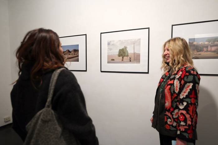 Fila di fotografie incorniciate lungo una parete bianca della galleria