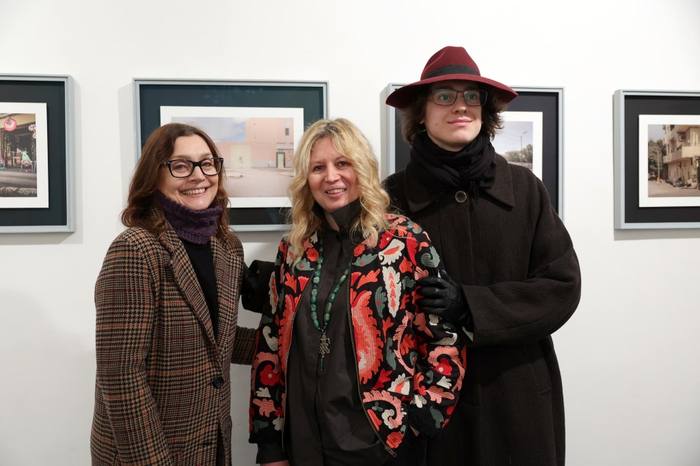 Camilla Boemio in posa con due ospiti davanti alle fotografie in mostra durante l&rsquo;inaugurazione